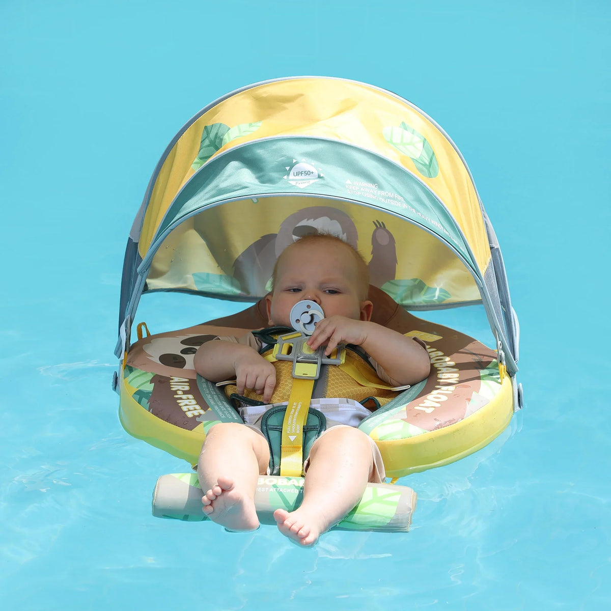 Baby sitting in the Mambobaby Sloth float in a pool with the sun canopy up